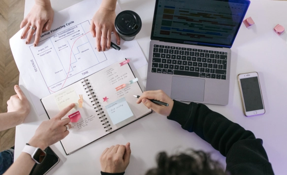 A table with a laptop, a notepad, smartphone.