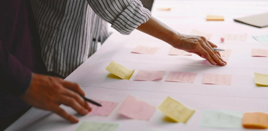 A hand at a table with several notes.