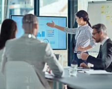 A group of people in an office looking at a screen with graphs.