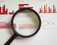 A close up of a magnifying glass with graphs in the background.